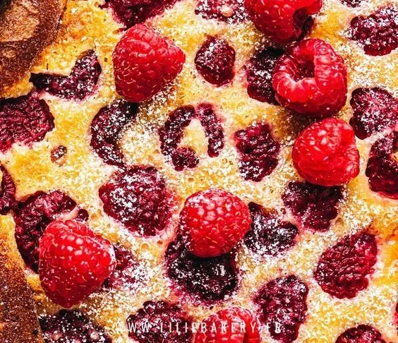 Clafoutis Framboise servi dans une assiette avec des framboises fraîches.