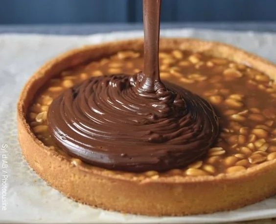 Tarte chocolat cacahuètes et caramel sur une assiette délicatement décorée