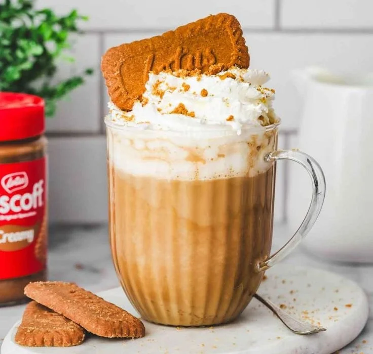 Une tasse de Latte Spéculoos garnie de crème et de biscuits de spéculoos.
