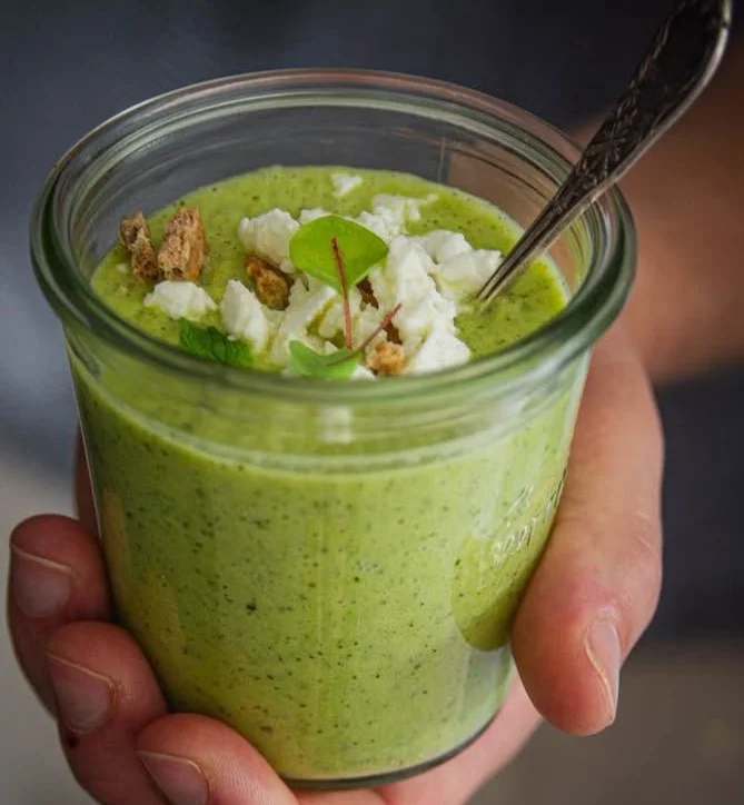 Soupe froide à la courgette servie dans un bol avec des herbes fraîches.