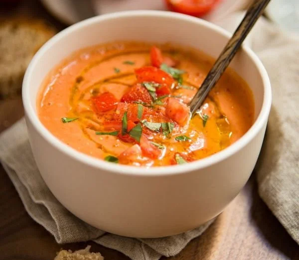 Soupe froide de tomates servie dans un bol avec des herbes fraîches