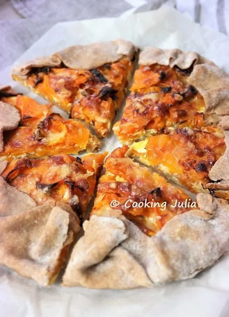 Tarte rustique aux oignons, butternut et cheddar, garnie de légumes frais.