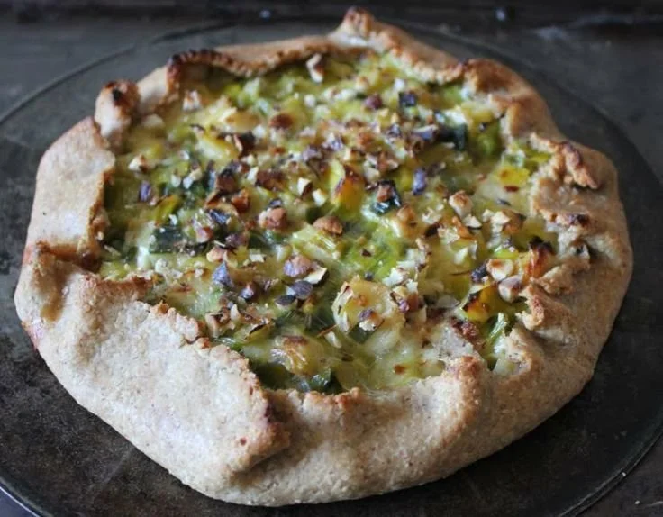 Tarte rustique aux poireaux et chèvre, garnie de noisettes.