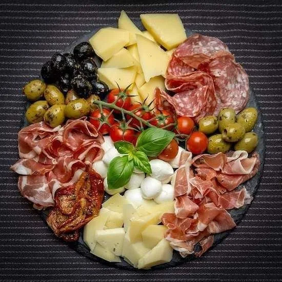 Plateau de charcuterie décoré avec des mets variés pour une présentation festive.