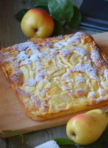 Gâteau moelleux à la poire sur un plat, décoré de tranches de poire et sucre glace.