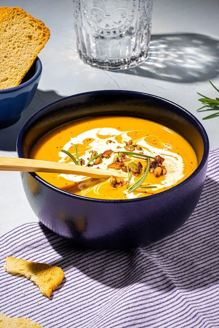 Bol de potage courge butternut garnie d'herbes fraîches