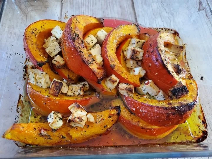 Potimarron rôti à la fêta dans un plat, décoration avec des herbes fraîches