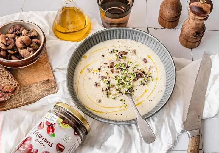 Un bol de velouté de panais avec des châtaignes et des morceaux de pain d'épices.